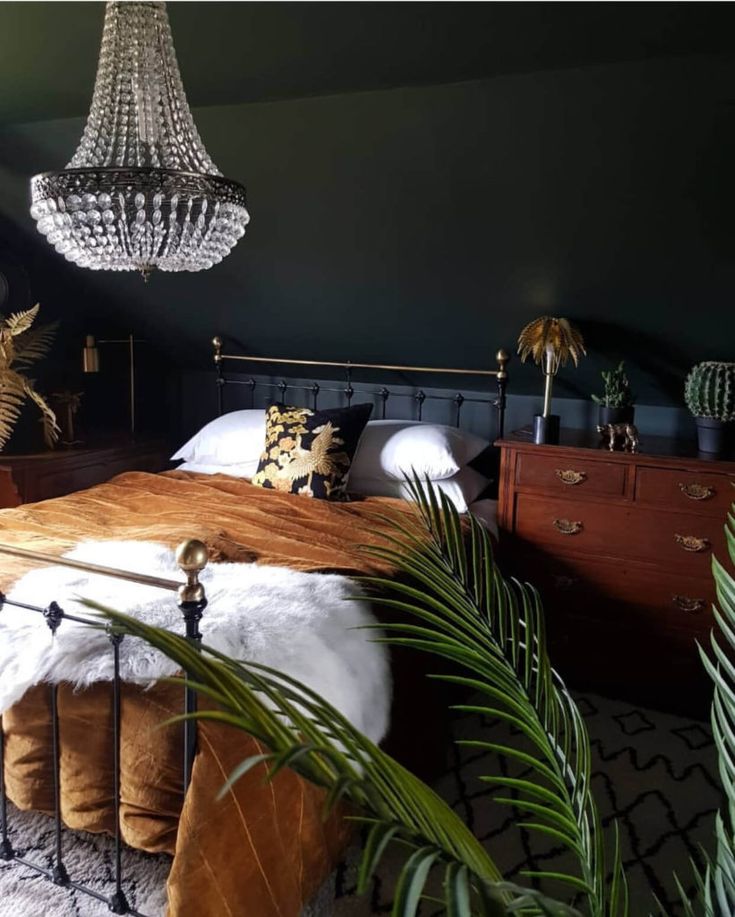 a bedroom with a bed, chandelier and plants in the corner next to it