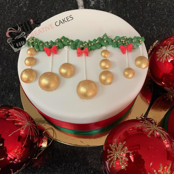 a decorated cake sitting on top of a table next to christmas ornaments and baubles