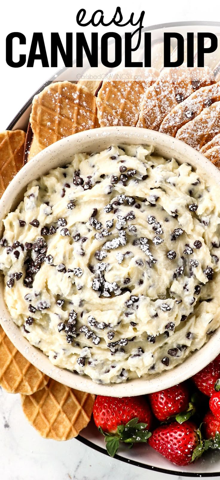 a bowl filled with cream cheese dip surrounded by crackers and strawberries on a plate