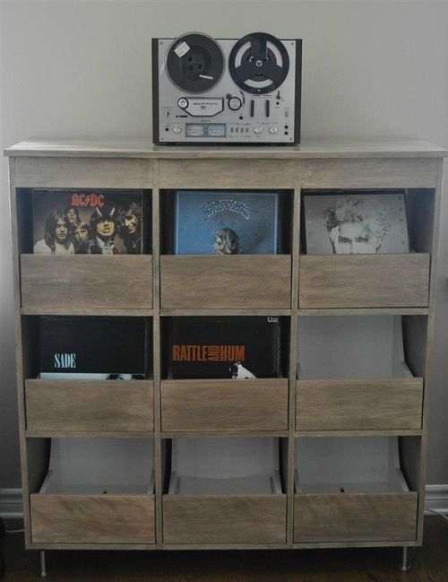 a record player sitting on top of a wooden shelf filled with vinyl records and cds