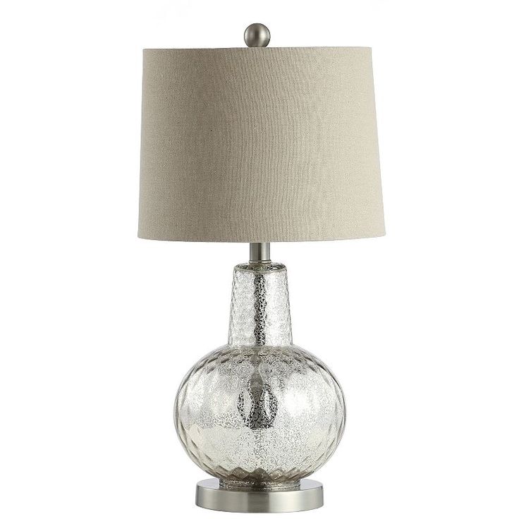 a glass table lamp with a beige shade on the base and a white linen lampshade