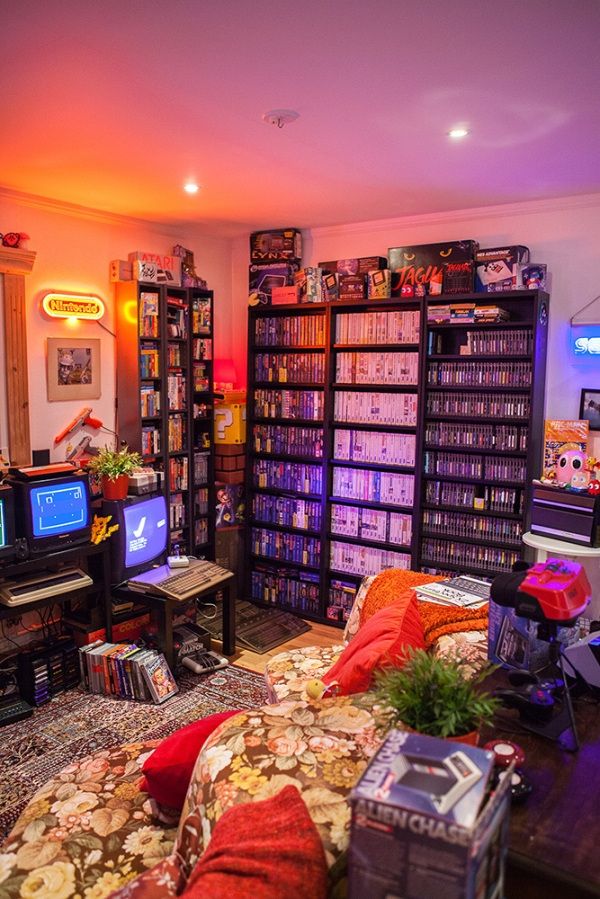 a living room filled with lots of furniture and bookshelves covered in video games