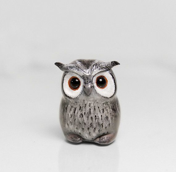 an owl figurine sitting on top of a white surface with eyes wide open