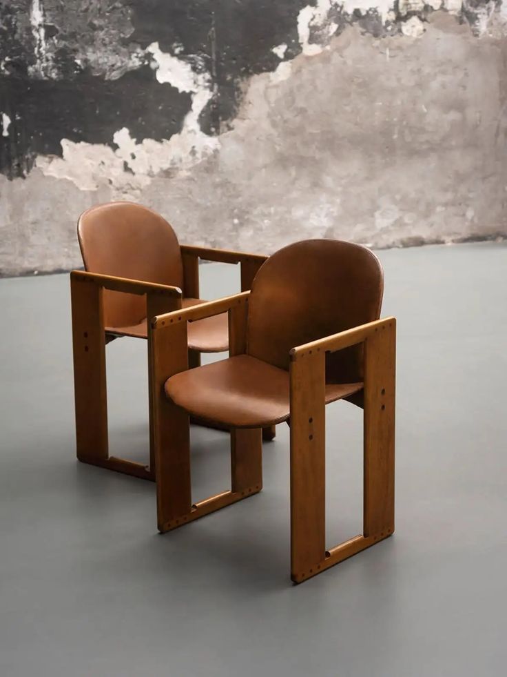 two chairs sitting next to each other in front of a wall