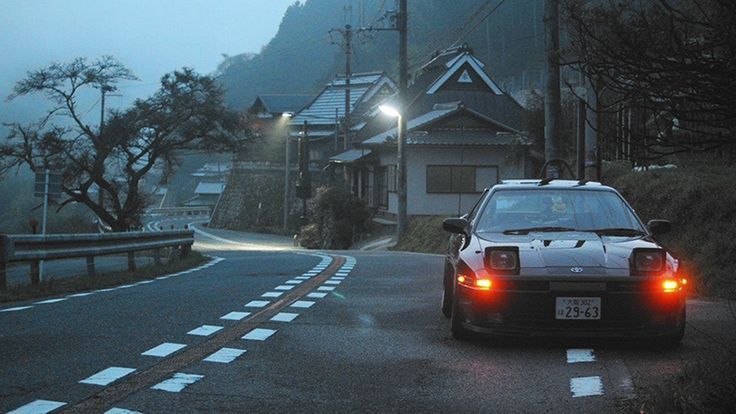 the car is driving down the road in the foggy area with houses on both sides