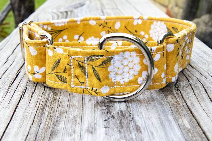 a yellow floral dog collar on a wooden deck with a metal ring in the center