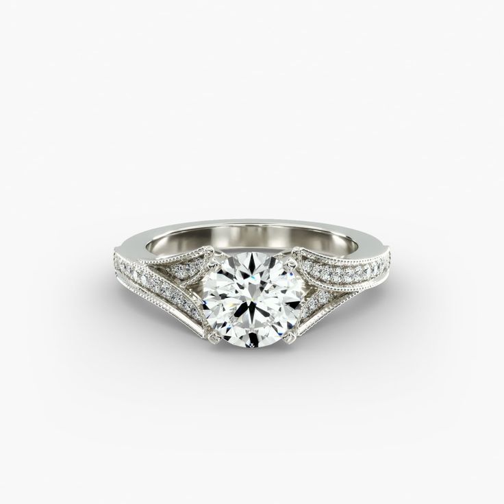 a white gold engagement ring with diamonds on the sides and an intricate band around it