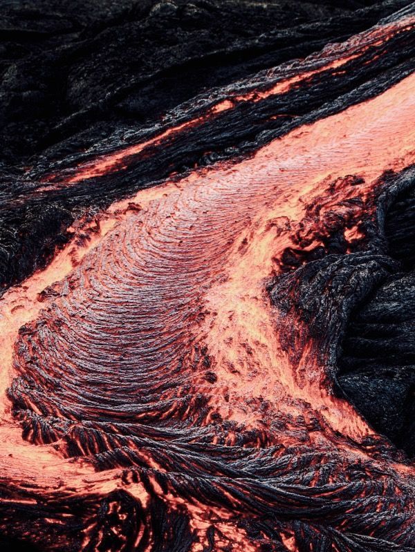 an aerial view of lava in the ocean with red and black waves coming out of it