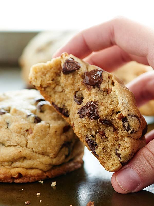 a person is holding a chocolate chip cookie in their left hand and the other one has it's bite taken out