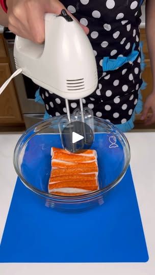 a woman is using an electric hand mixer to make carrot cake in a bowl on a blue mat