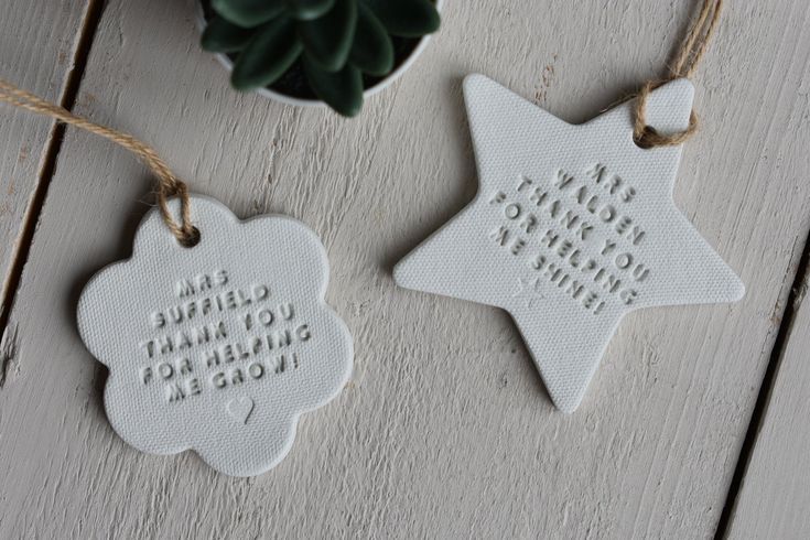 two white ceramic ornaments with words on them