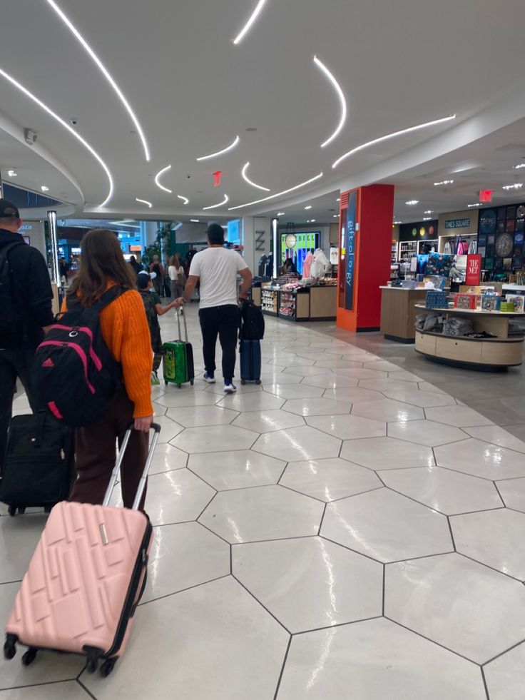 people are walking through an airport with their luggage