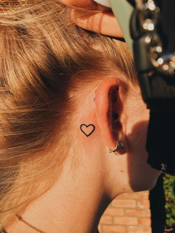 a woman with a small heart tattoo behind her ear