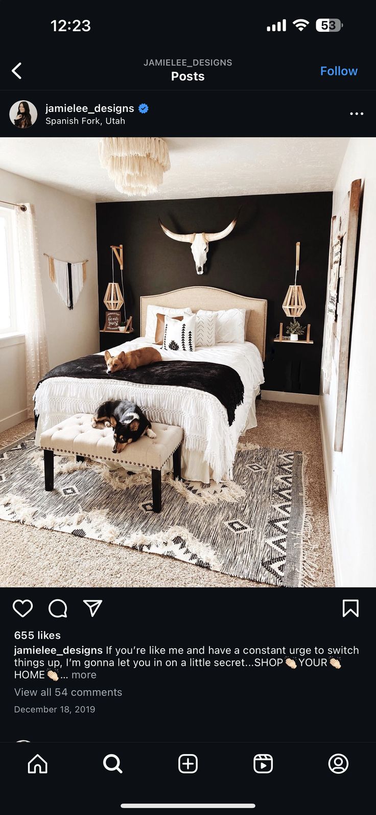 a bed room with a neatly made bed and a cow skull on the wall above it