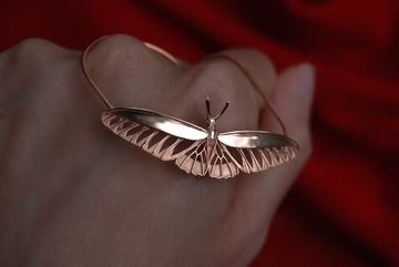 a close up of a person's hand with a butterfly ring on it