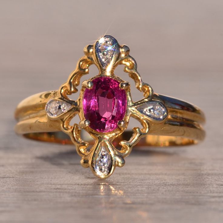 a close up of a ring with a pink stone and diamond set in the middle