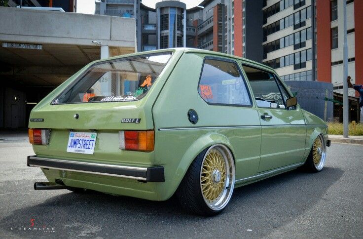 a green car parked in front of a tall building