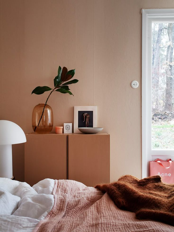 a bedroom with a bed, nightstand and plant on top of the dresser next to it