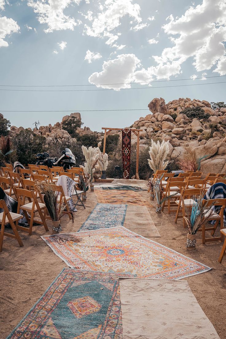 an outdoor ceremony setup with chairs and rugs