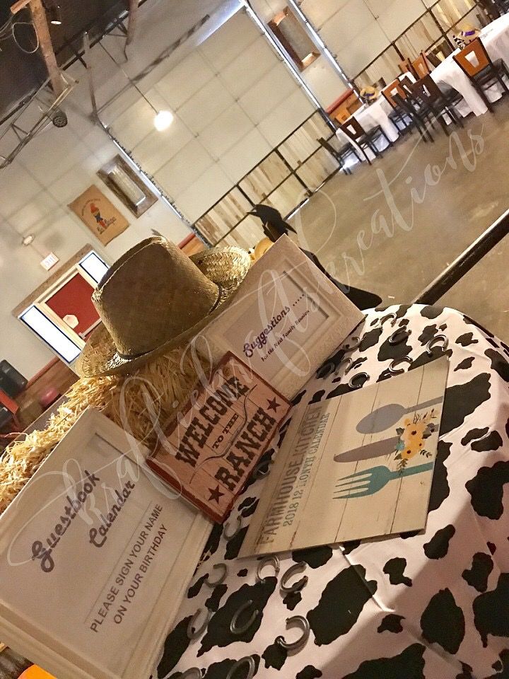 an open book sitting on top of a cow print table cloth next to a hat