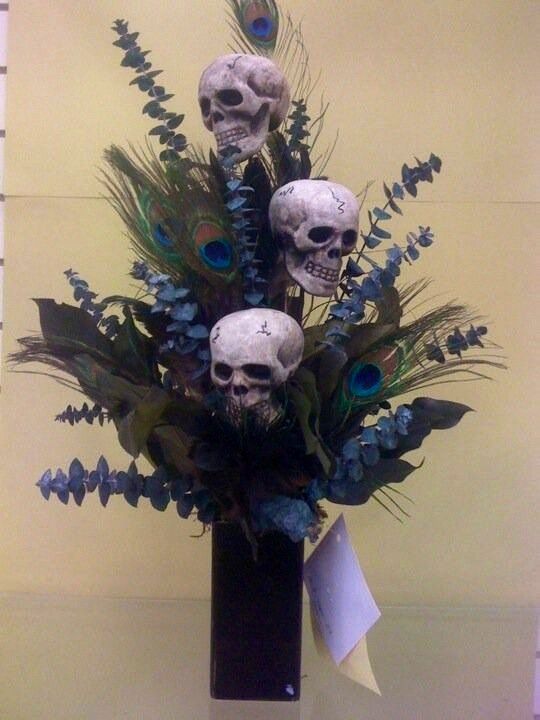 there are three skulls in the vase with blue flowers and feathers on it's head