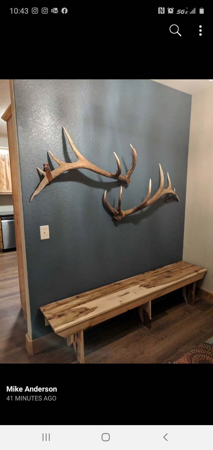 a wooden bench sitting in front of a wall with antlers on it