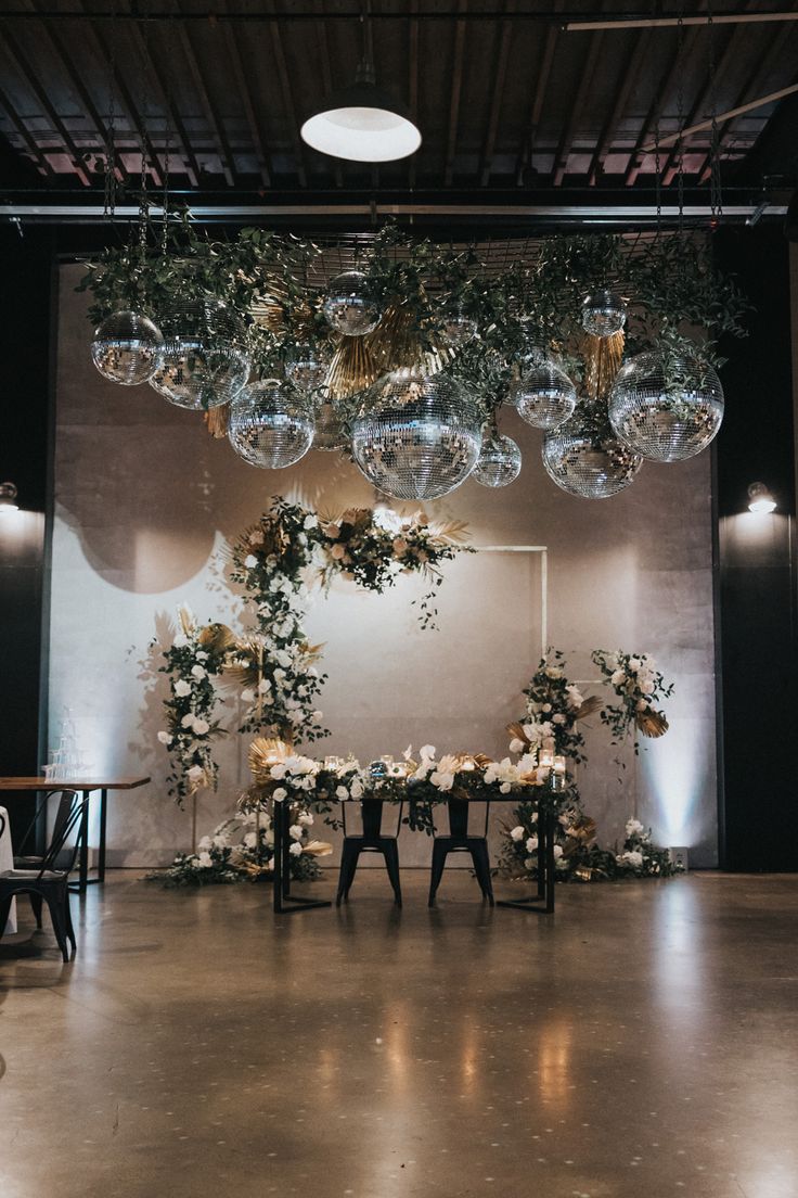 an elegant wedding reception setup with hanging glass globes and greenery