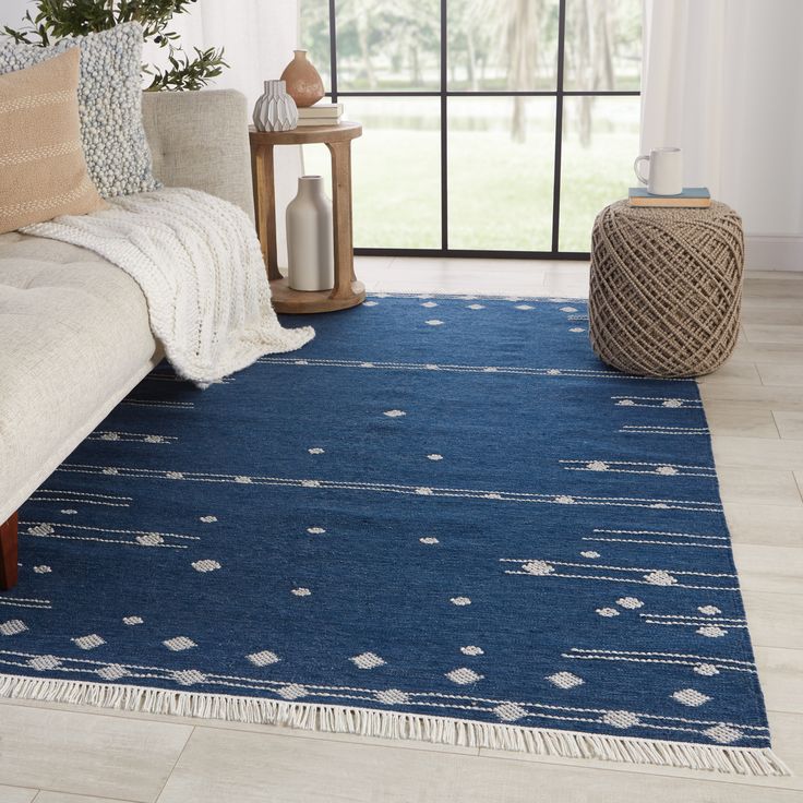 a living room area with a blue rug on the floor and a window in the background