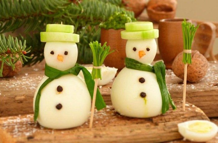 two snowmen made out of marshmallows sitting on top of a wooden board