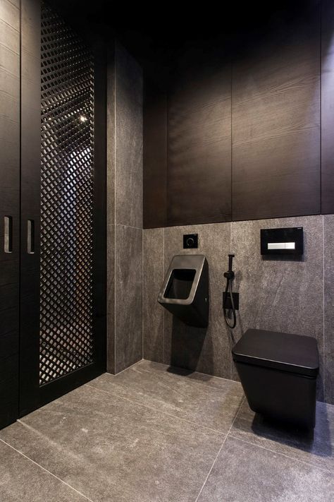 a public restroom with a black toilet and urinal on the wall next to it