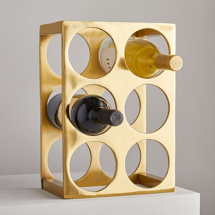 a wine bottle holder made out of gold metal with holes in the middle and two bottles on each side