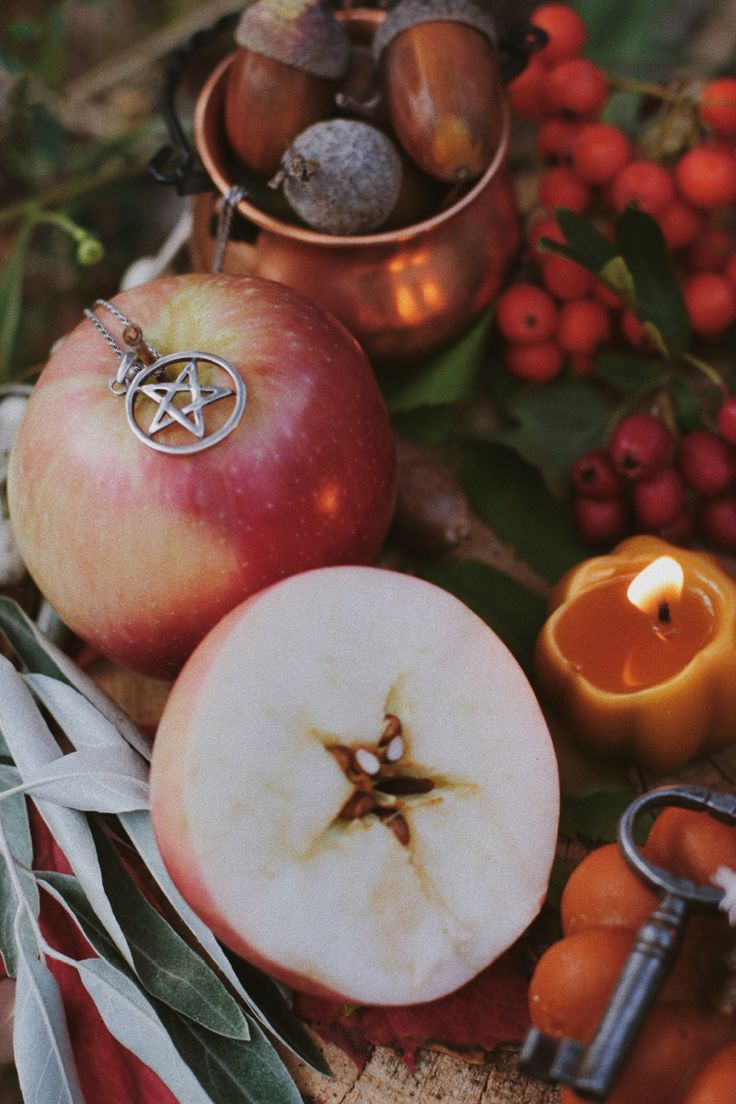 apples, candles and other items are arranged on a piece of wood with leaves in the foreground