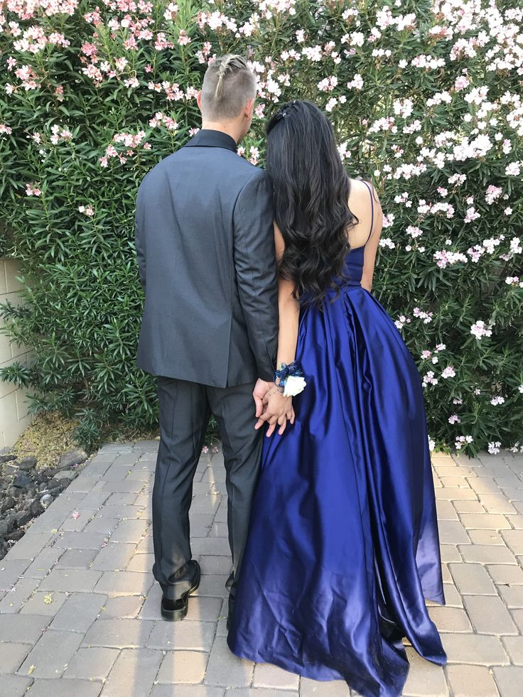 a man and woman in formal wear standing next to each other on a brick walkway