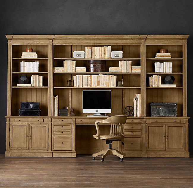 a computer desk sitting in front of a wooden bookcase