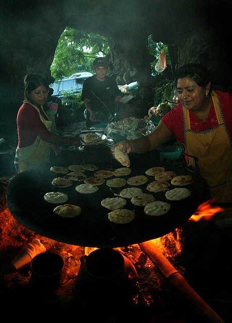 people cooking food on an outdoor grill in the dark