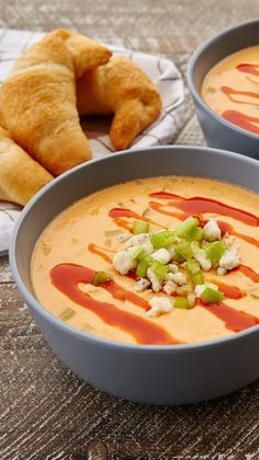 two blue bowls filled with soup next to croissants