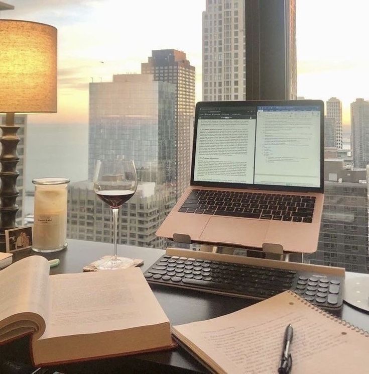 an open laptop computer sitting on top of a desk next to a book and pen