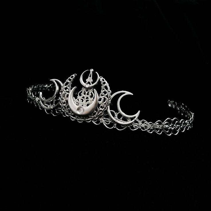 Selene Tiara Part of our New Moon range, this beautiful tiara is adorned with silver moons and tiny silver rhinestones. Perfect to add a witchy vibe to your outfit. The outer rim is lined with heart shaped filigree.  Why not check out our chokers and earrings to make a matching set! Handmade to order, ready in 1-2 weeks. ------------------------------------------------- Headwear Guide -Headwear comes in one size which is flexible . -Do not submerge in water or in intense heat as this may cause wear damage to the item. -Customisations can be requested before purchase such as other colours, different adornments, gem colours etc. The level of change may result in additional costs. -As these items are handmade, small variations may occur. We try to replicate each item as accurately as possible Witch Headpiece, Luna Goddess, Alternative Accessories, Gothic Crown, Gothic Engagement Ring, Goddess Crown, Triple Moon Goddess, Beautiful Tiaras, Wiccan Jewelry