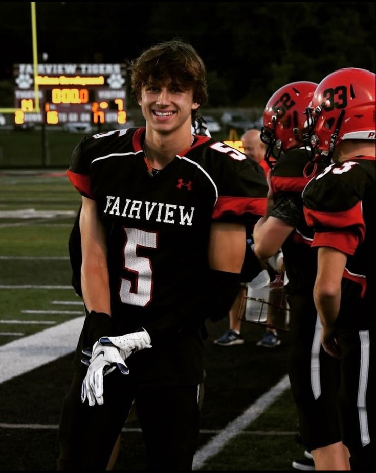 a football player is walking off the field with his team mates behind him at night