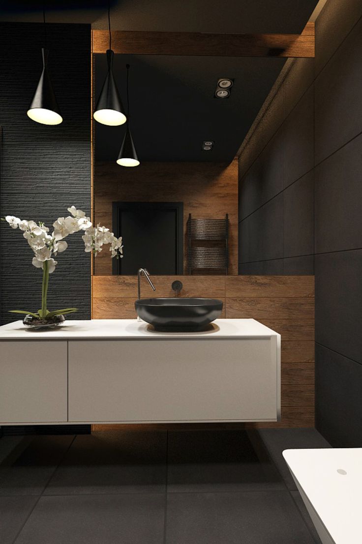 a bathroom with a sink, mirror and two lights above the sink is an orchid in a vase