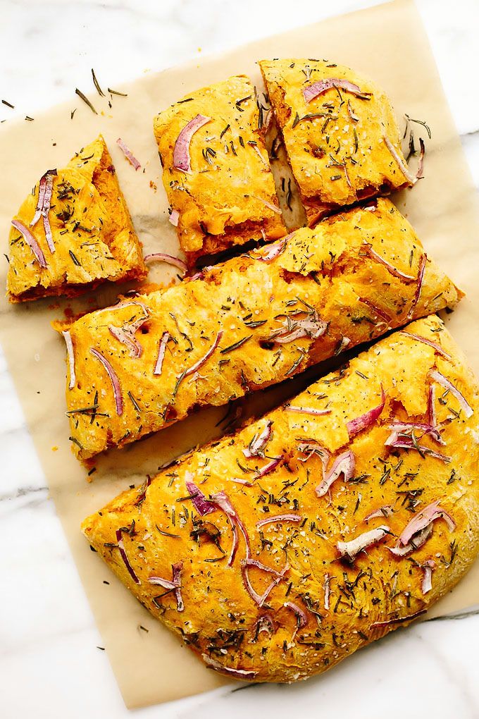 four pieces of bread with various toppings sitting on top of a piece of parchment paper