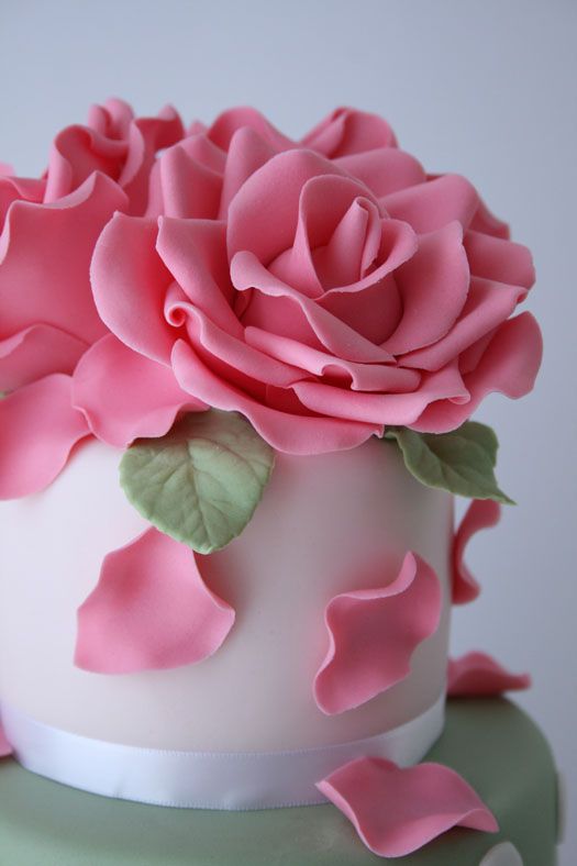 there is a pink rose on top of the cake, it looks like roses are coming out of the icing