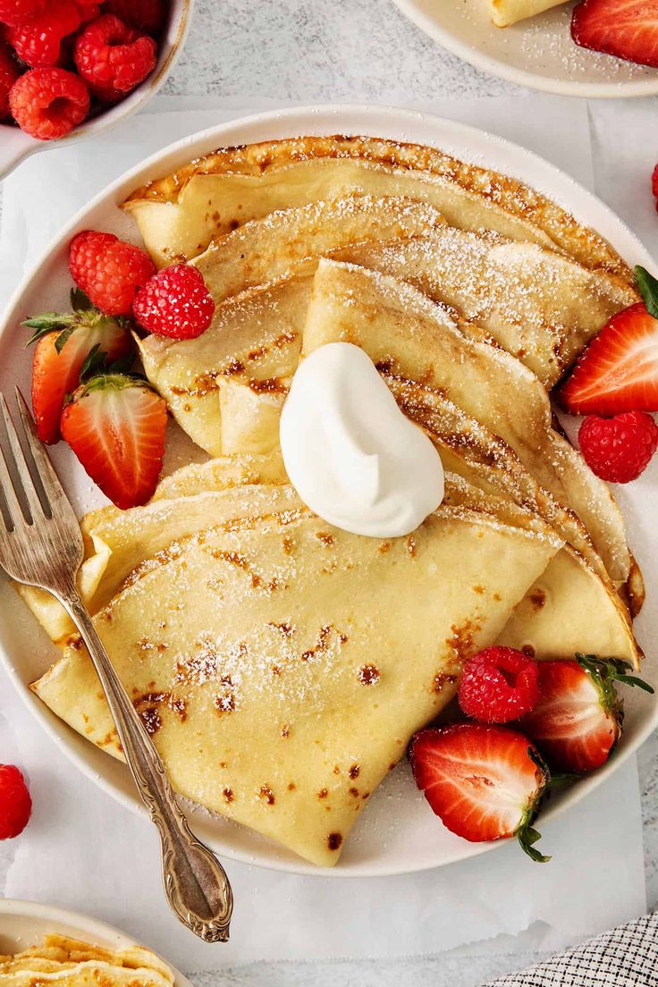 pancakes with whipped cream and strawberries on the side