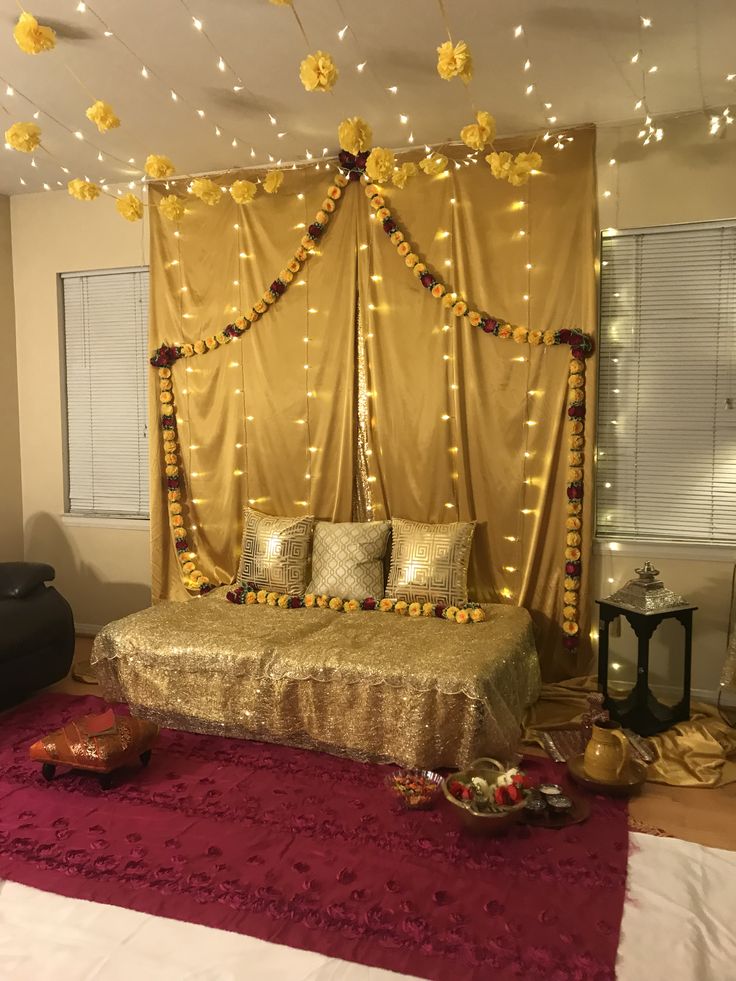 a bedroom decorated in gold and red with lights on the ceiling, bedding and pillows