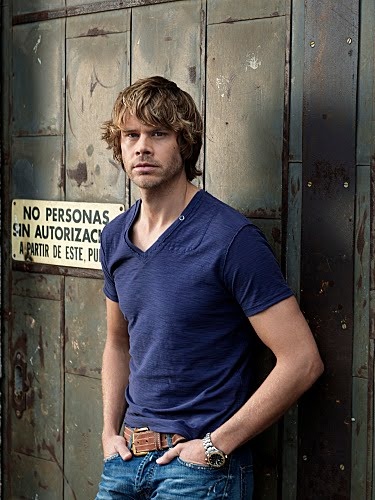 a man standing in front of a wooden door with his hands on his hips and looking at the camera