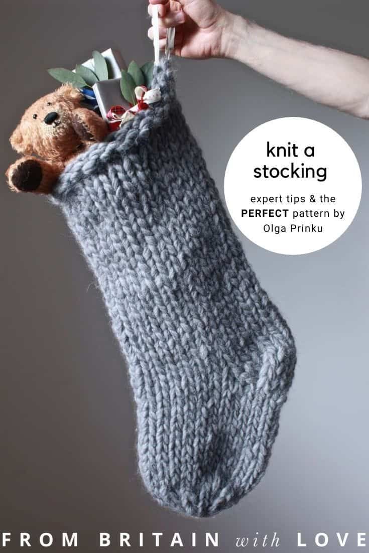 a hand holding a sock with knitting needles in it and a teddy bear sticking out of it