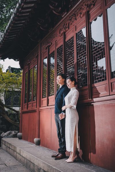 a man and woman standing next to each other in front of a building with red doors