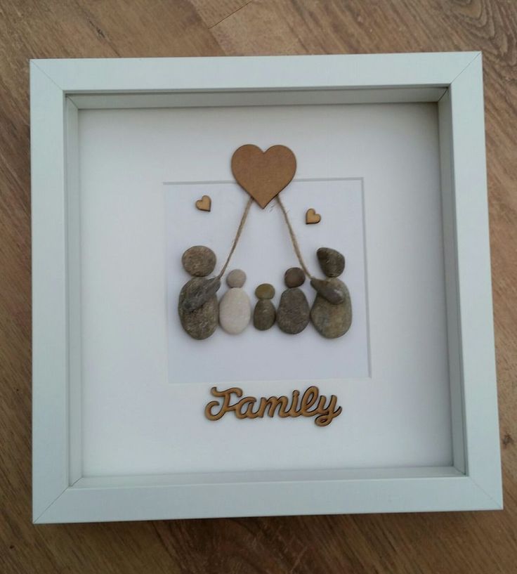 a white frame with some rocks in it and a heart hanging from the top that says family