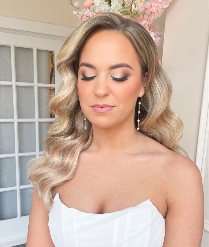 a woman with blonde hair wearing a white strapless dress and flowered headpiece