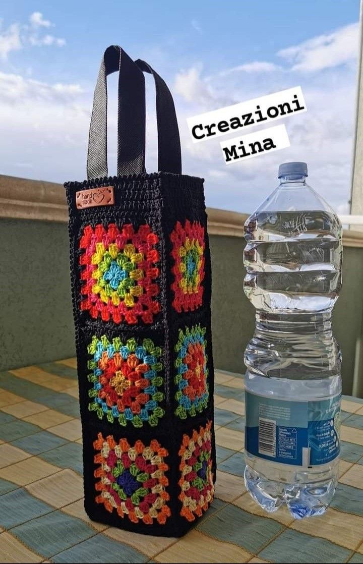 a crocheted bag sitting on top of a table next to a water bottle